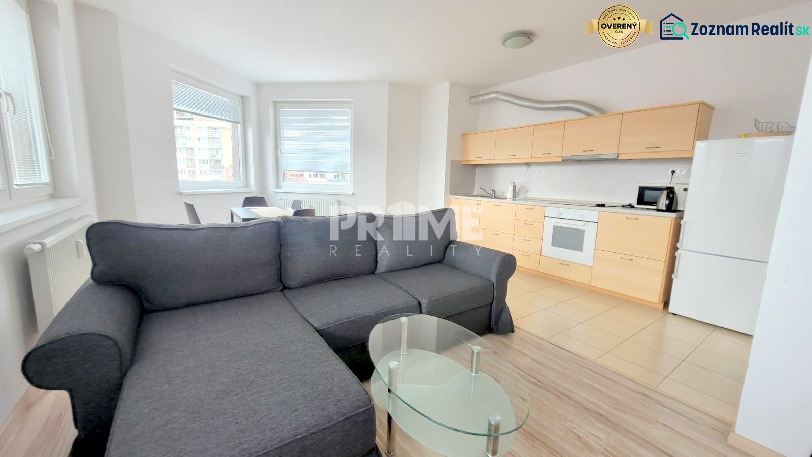 Living room of a two-room apartment with a kitchen, sofa, and glass table.