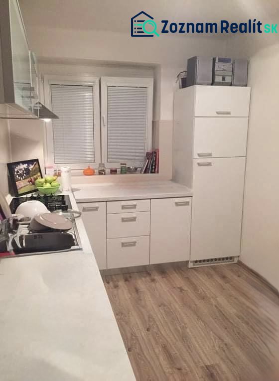 A kitchen in a 2-room apartment with white cabinets and a wood-patterned floor.