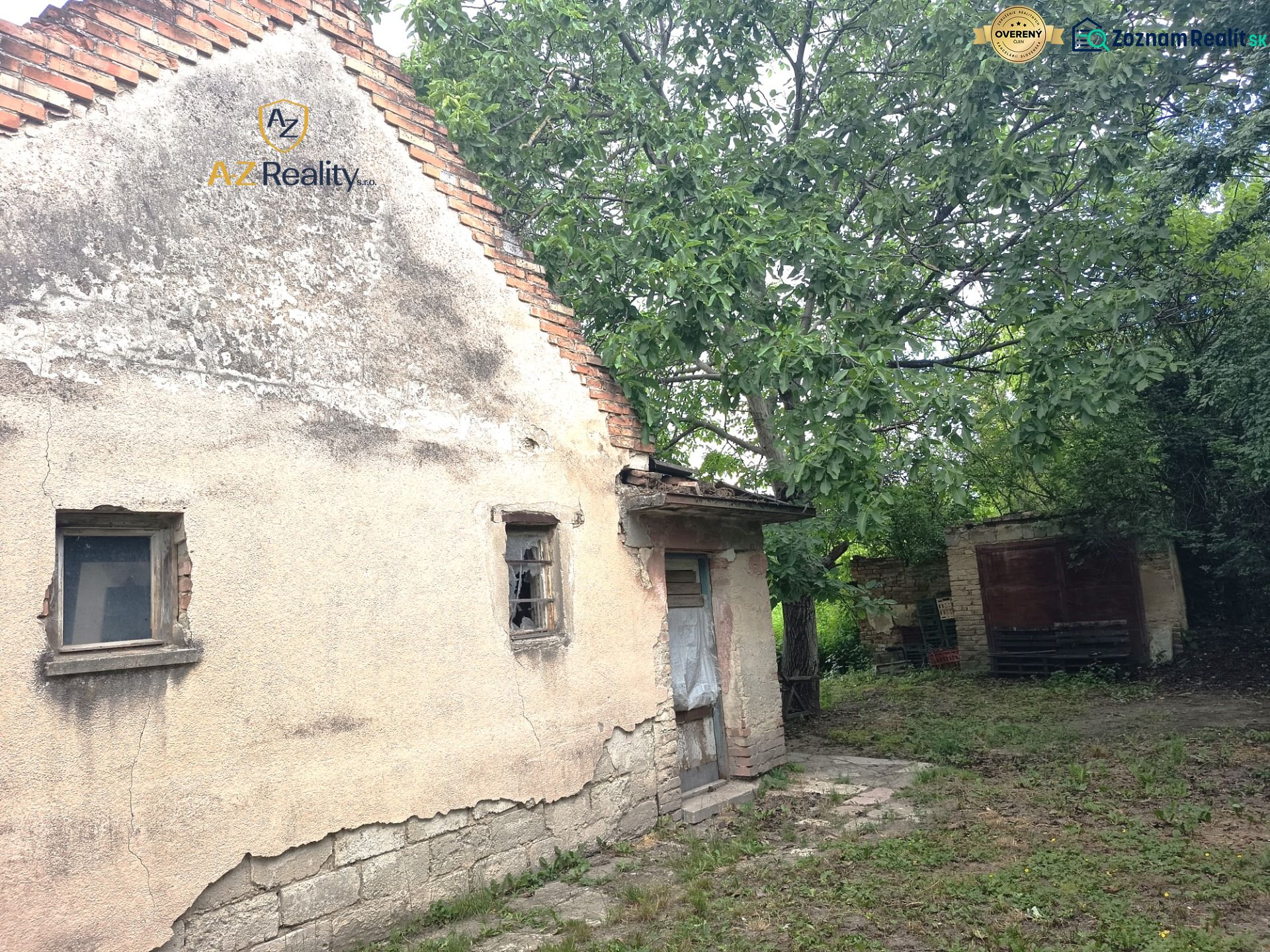 An older family house in Nové Zámky surrounded by greenery with damaged walls.