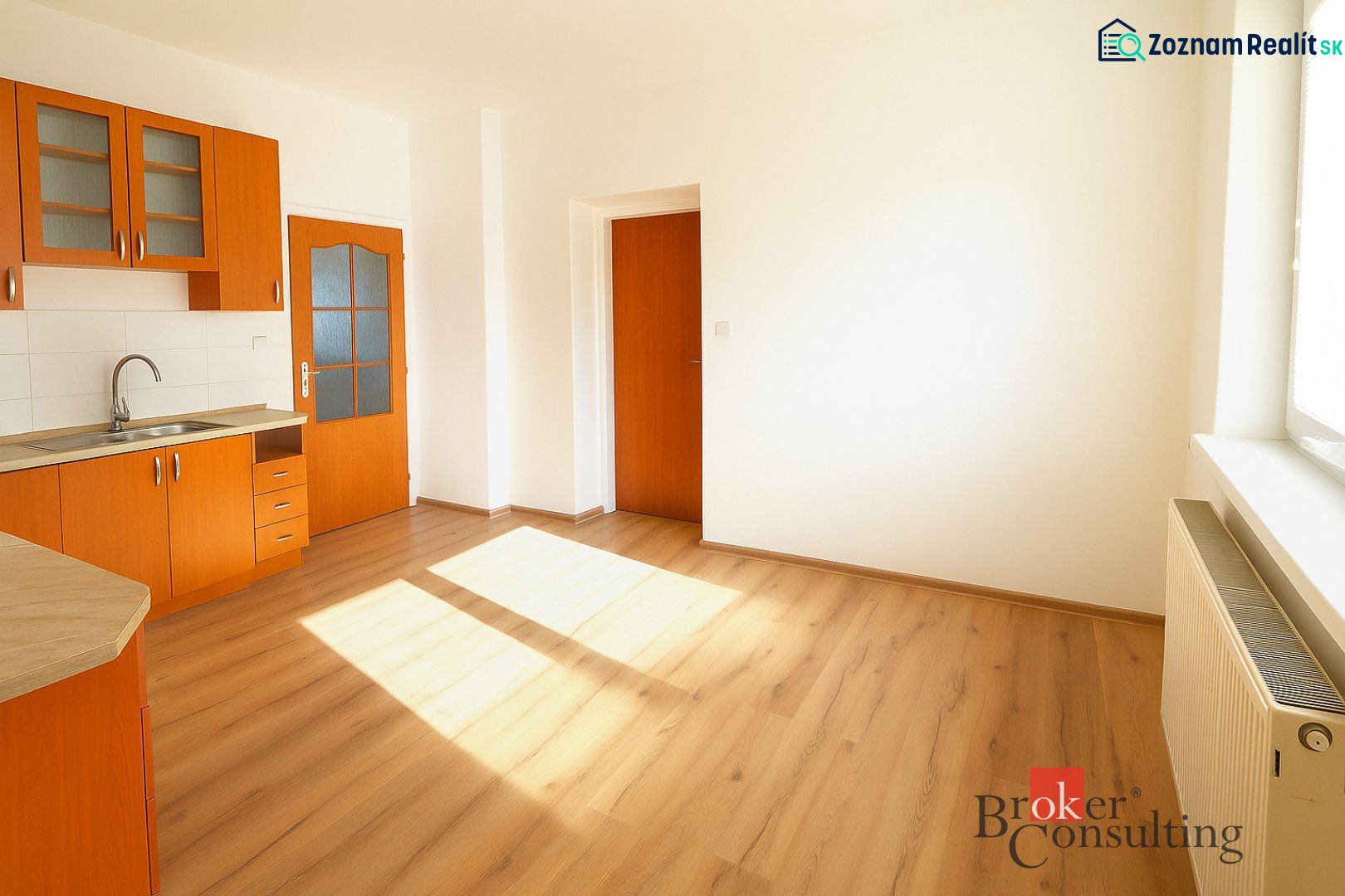A kitchen in a 2-room apartment with an orange kitchen unit and a floor with a wood pattern.