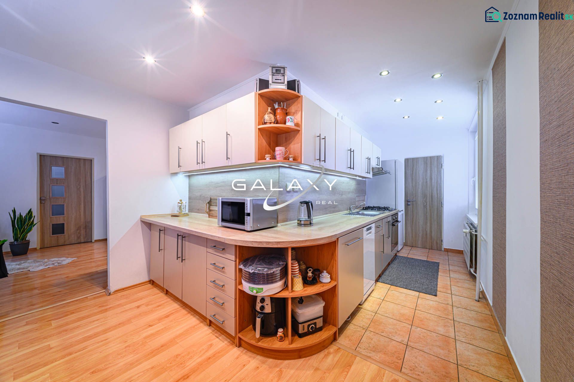 A kitchen in a 2-room apartment with a wooden decor floor and modern appliances.