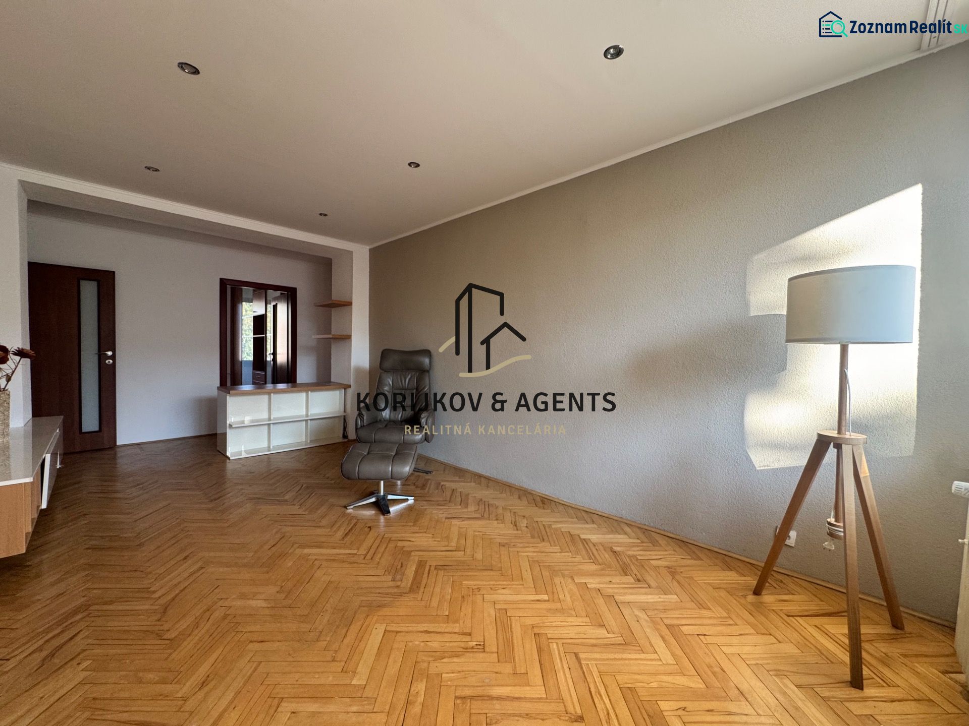 Living room in a 4-room apartment with a wooden decor floor and a comfortable armchair.