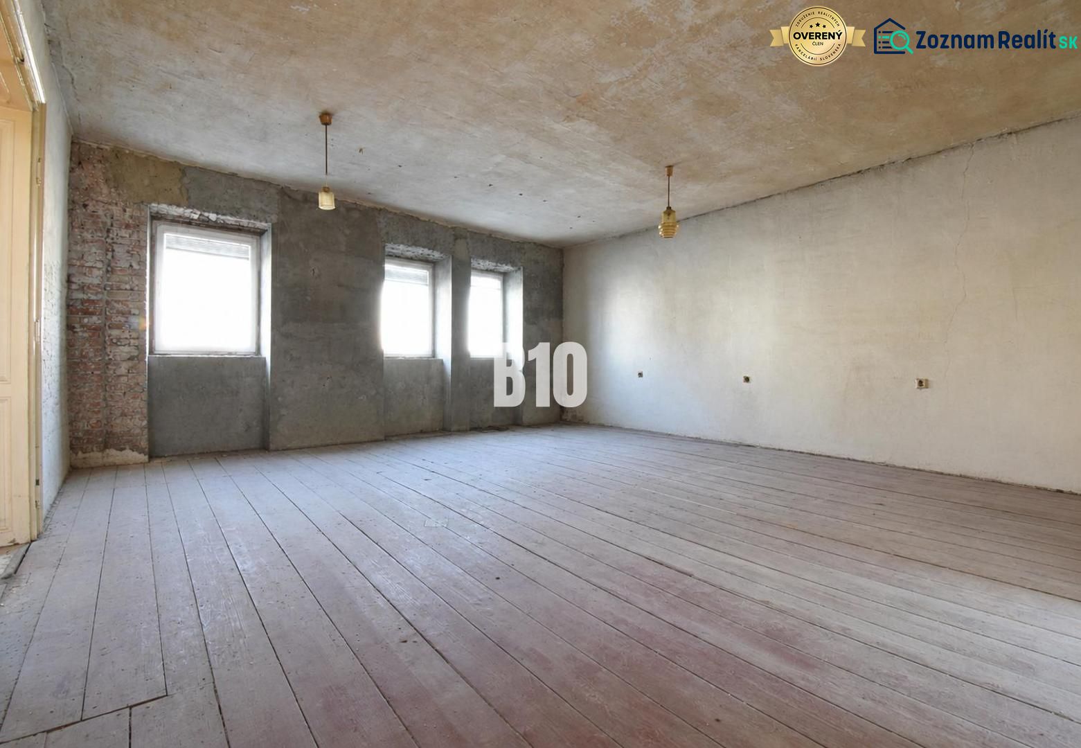 A spacious room with three windows and a wooden decor floor.