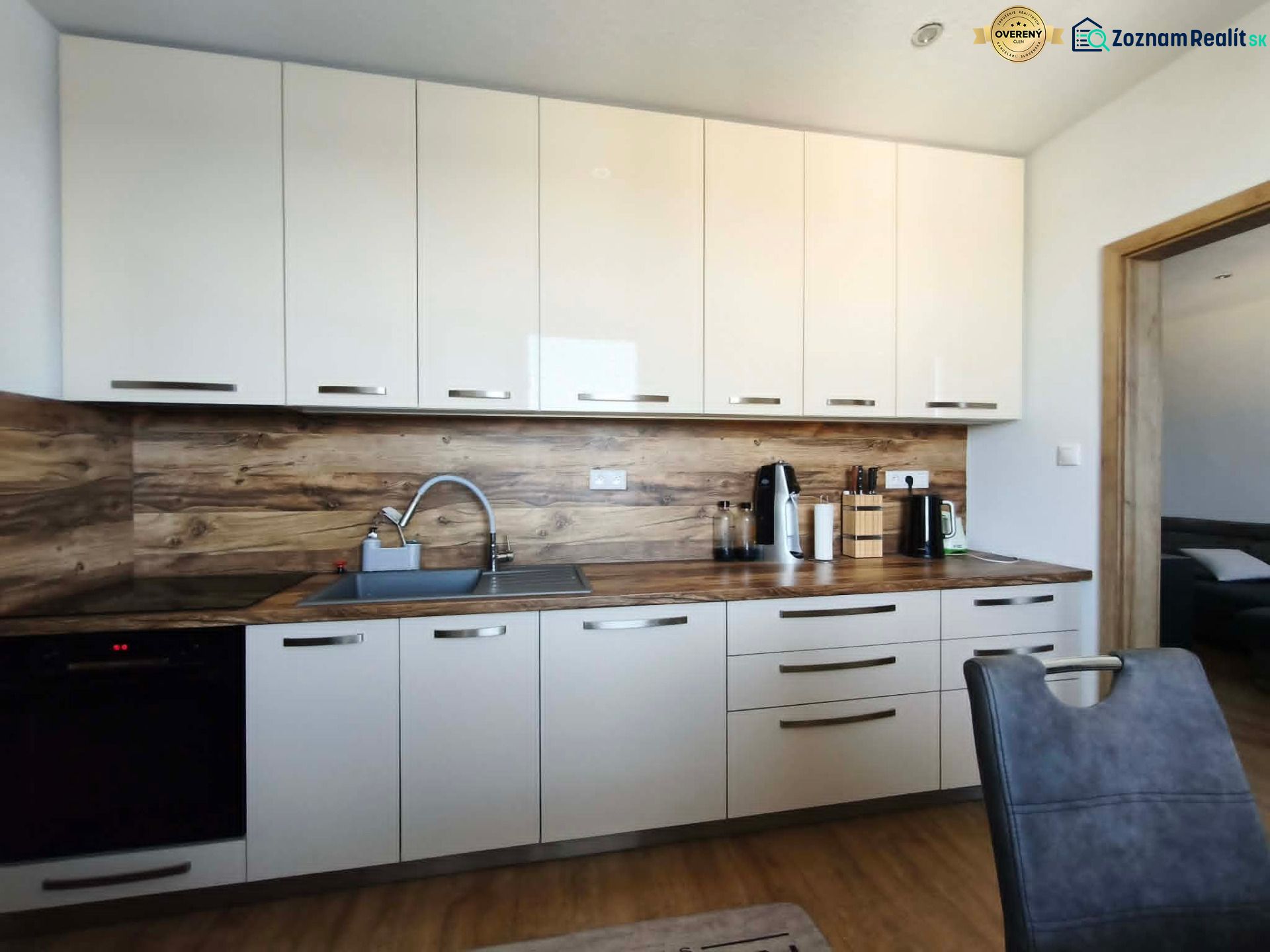 A kitchen in a 3-room apartment with white cabinets and a wood-patterned floor.