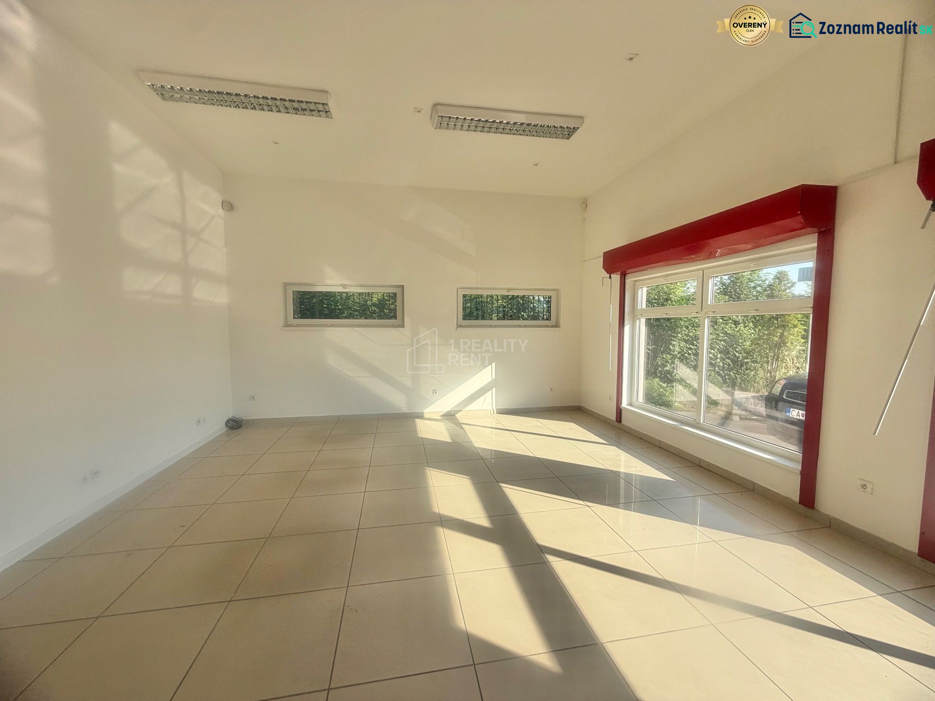 Interior of a commercial space with large windows and glossy tiles.