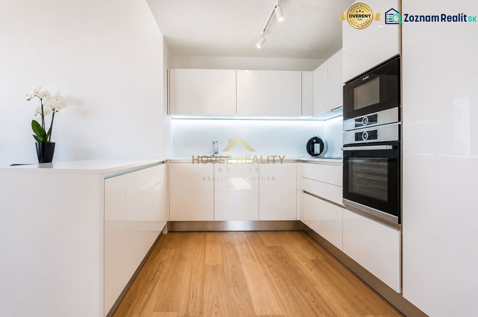 A kitchen in a 3-room apartment with white cabinets and a wooden-patterned floor.