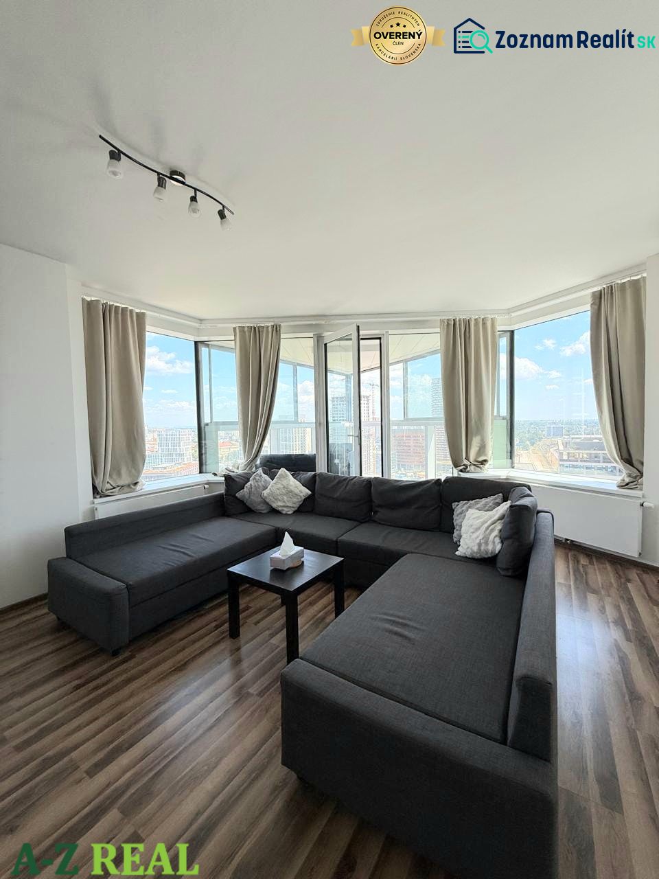 Spacious living room area with a dark sofa and wooden decor flooring in a 3-room apartment.