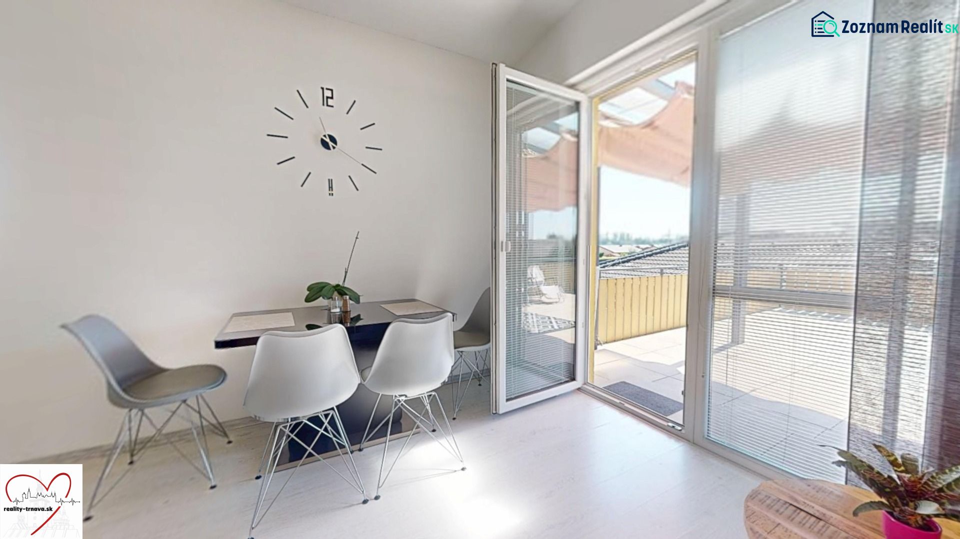 Dining area with a clock and an open balcony in a 3-room apartment.