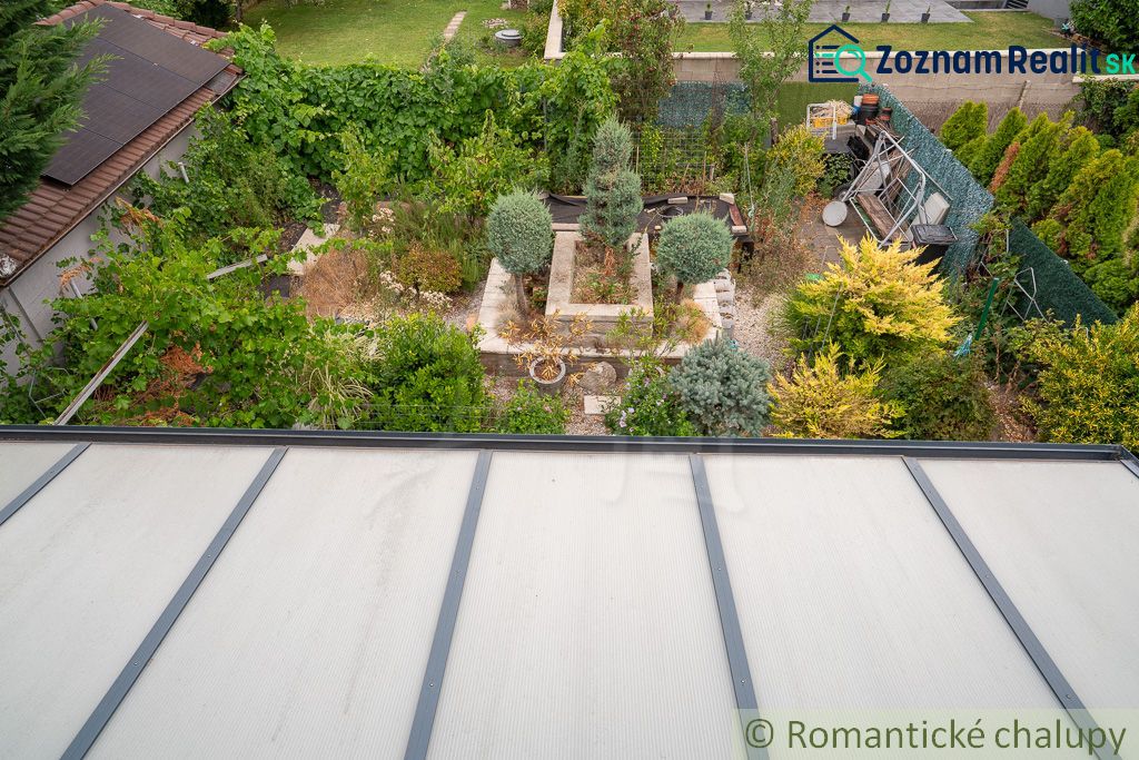 A garden by the cottage in Senec with rich greenery and a greenhouse.
