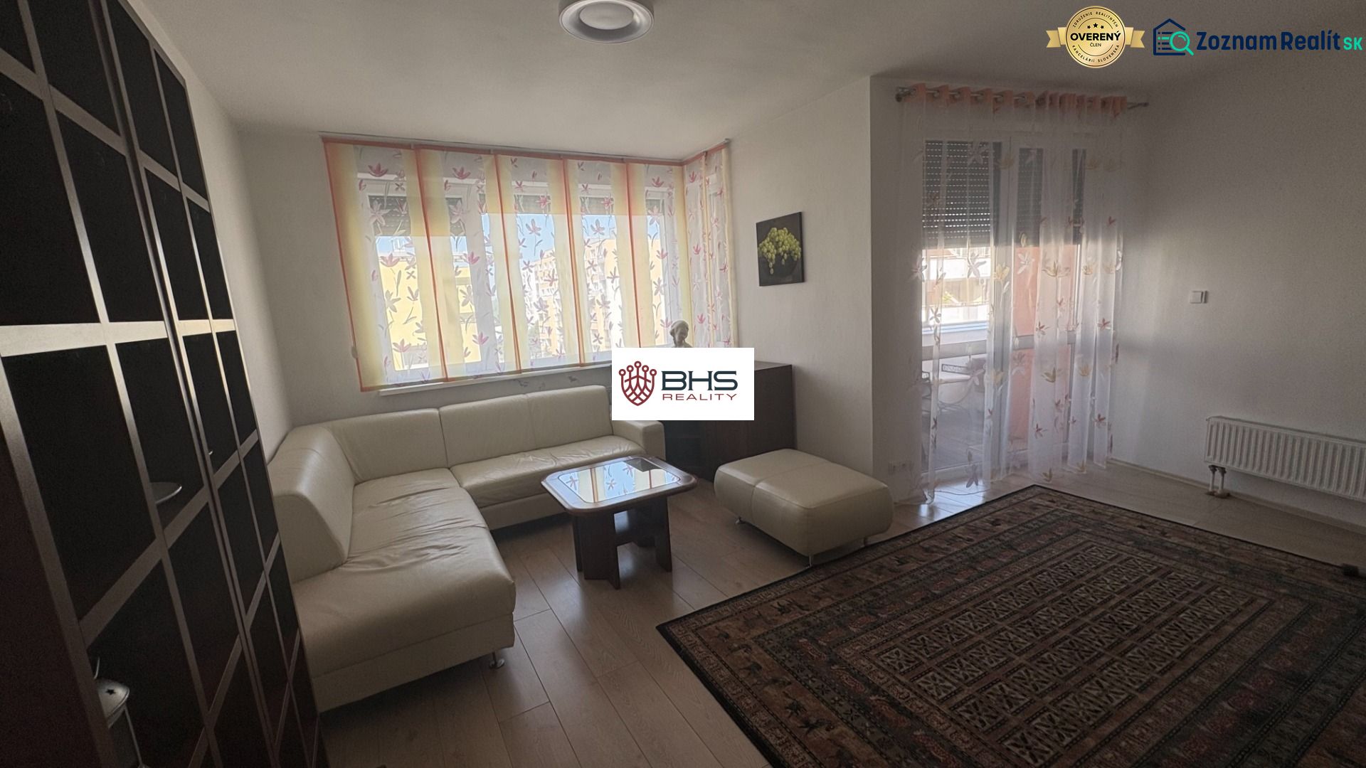 Living room with wood-patterned flooring, a corner sofa, and a carpet in a two-room apartment.