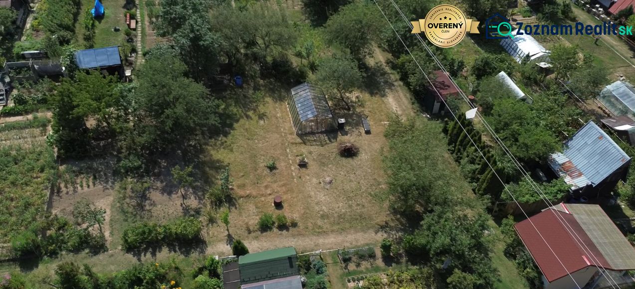 Gardens in Detva with a wooden structure, greenery, and greenhouses.