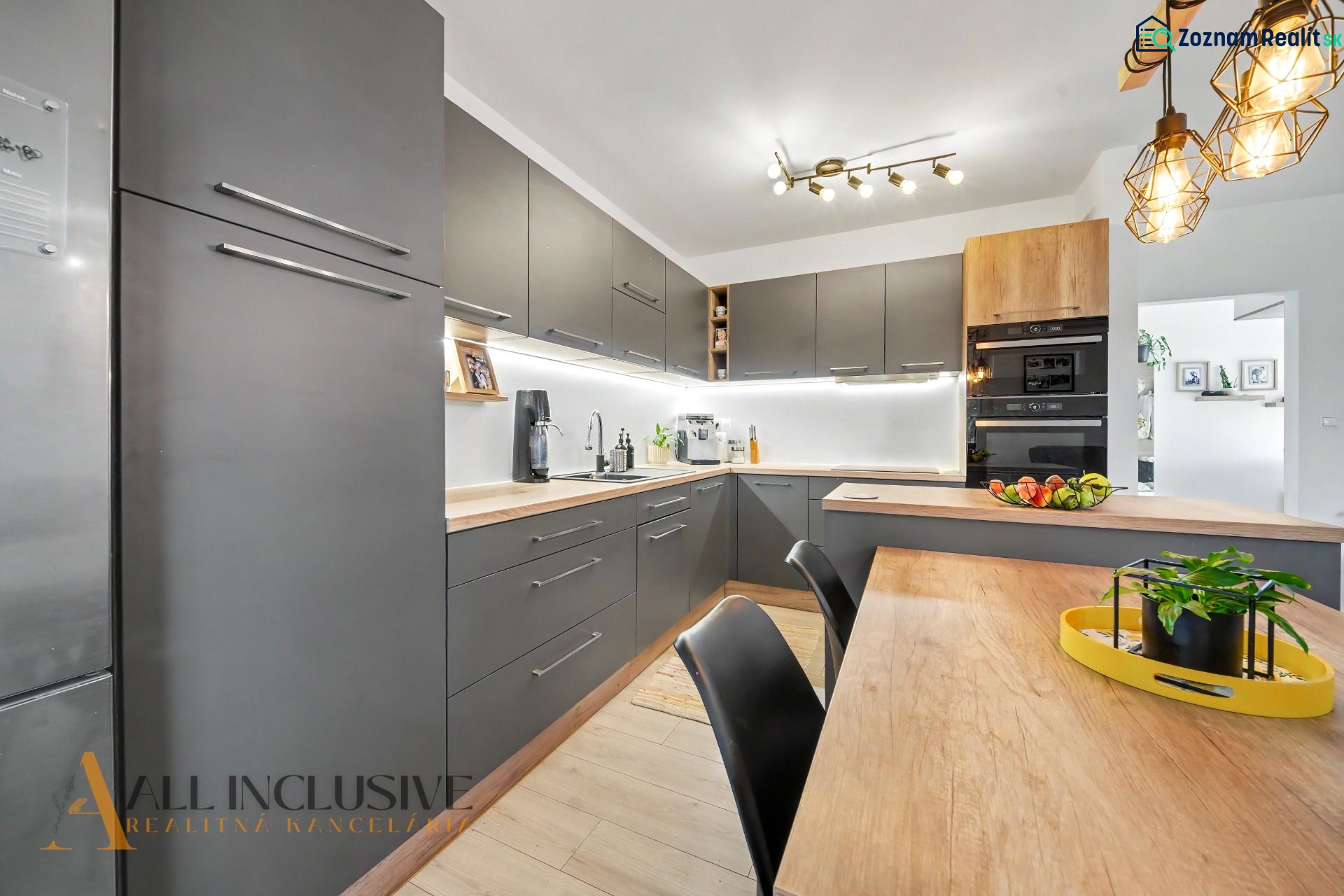 A kitchen in a 3-room apartment with dark cabinets and a wooden decor floor.