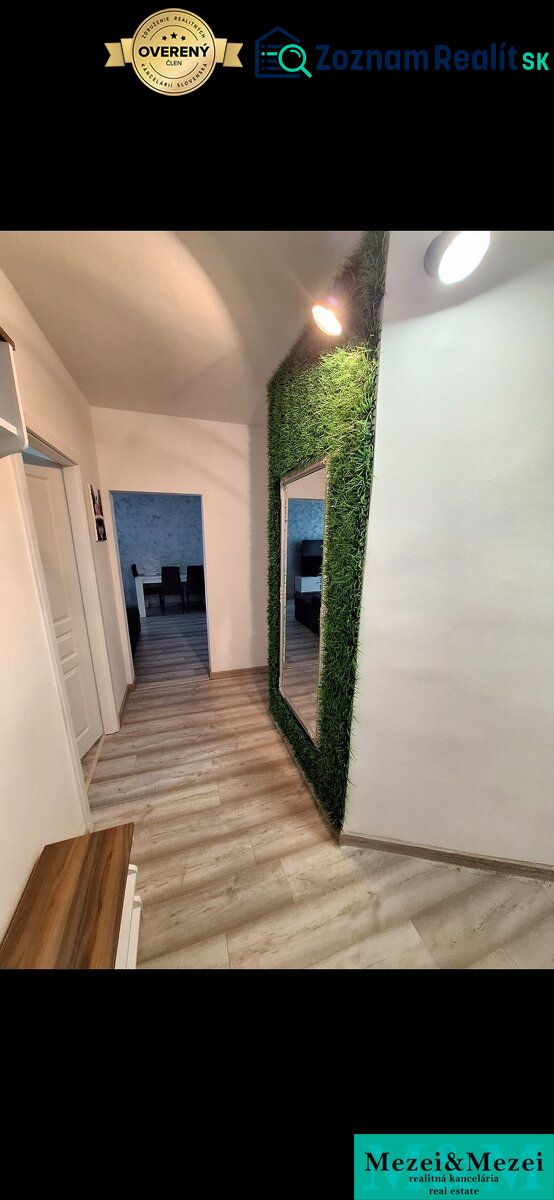 A hallway in a 3-room apartment with a wooden decor floor and a vertical garden.
