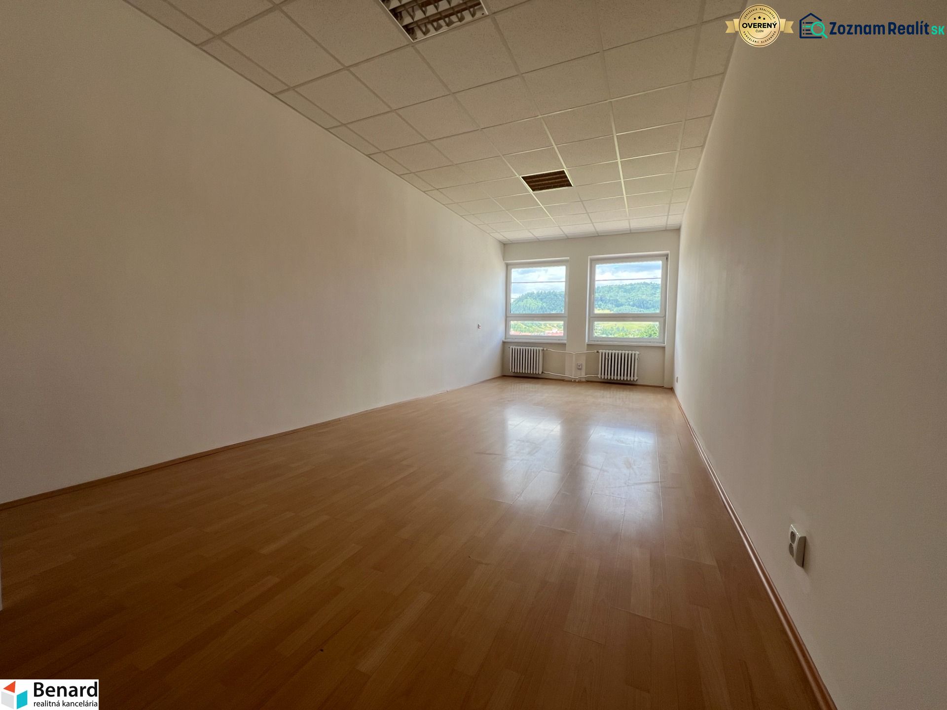 A spacious office with white walls and a wooden decor floor.