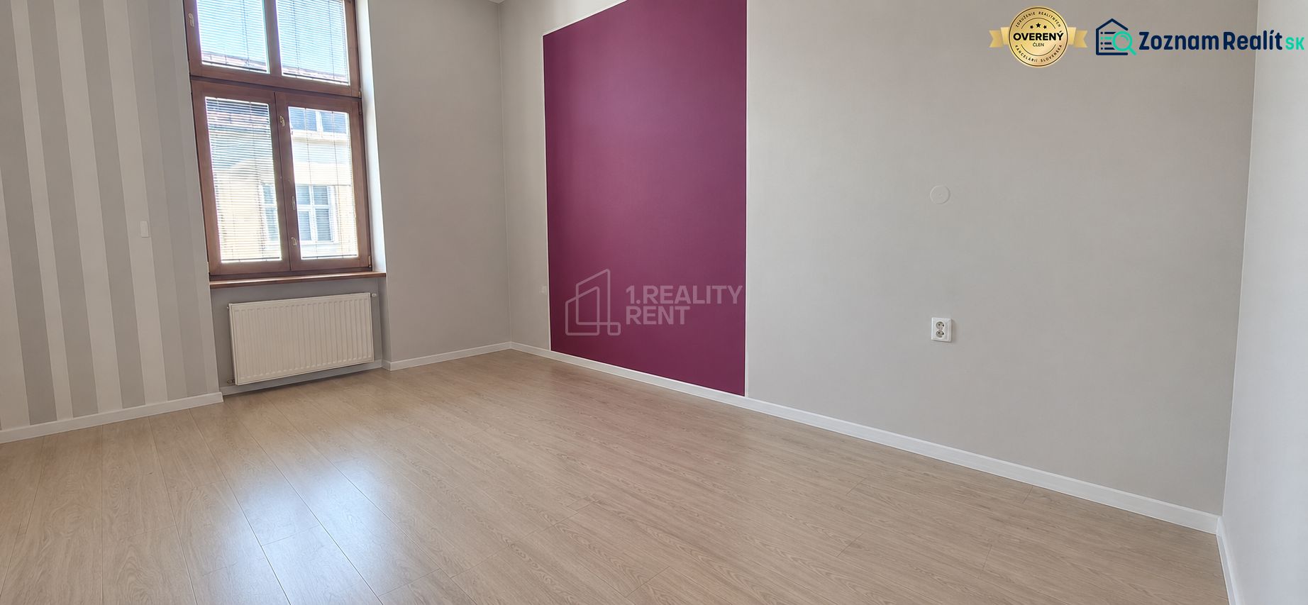 An office interior with wood-patterned flooring and a purple accent wall.