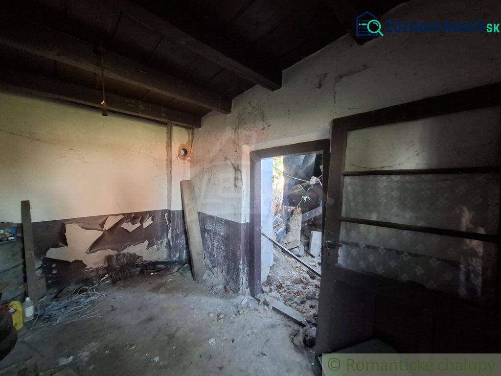 The interior of a family house with peeled walls and open doors leading outside.