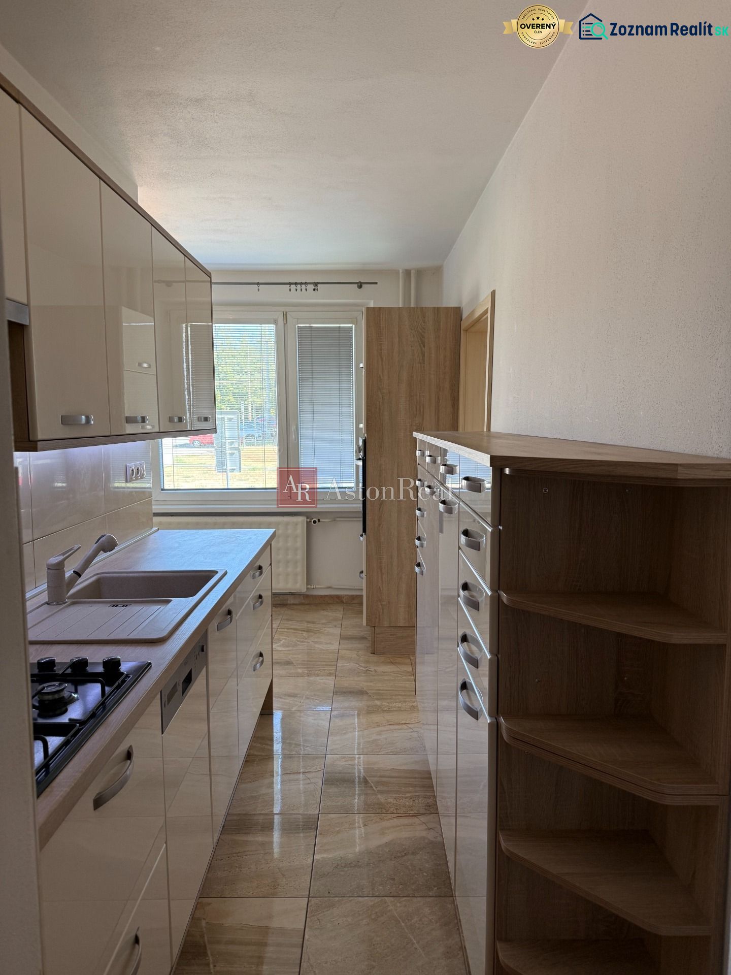 A kitchen in a 3-room apartment with tiles and light kitchen cabinets.
