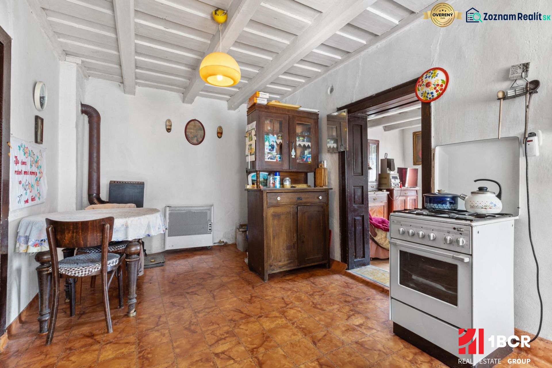 A kitchen in a family house with a stove, a cooker, and wooden furniture.