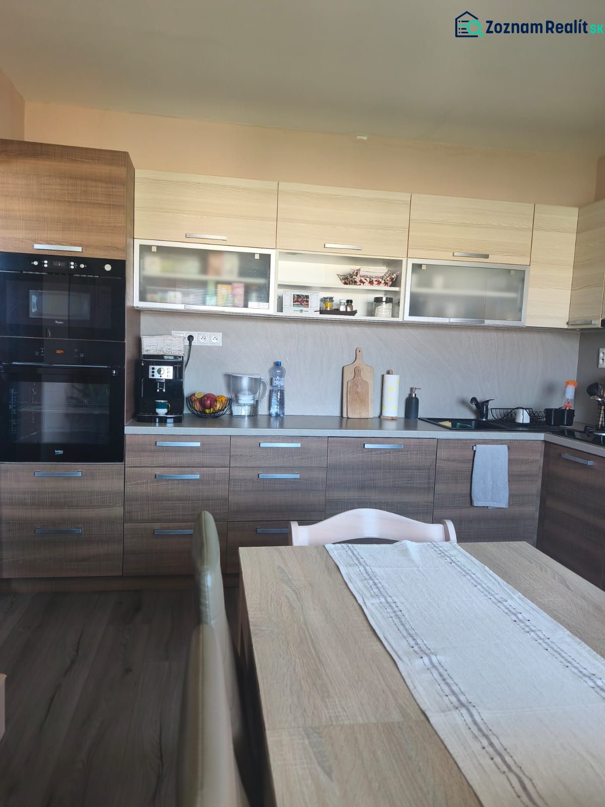 A kitchen in a 3-room apartment with a wooden decor floor, a dining table, and a kitchen unit.