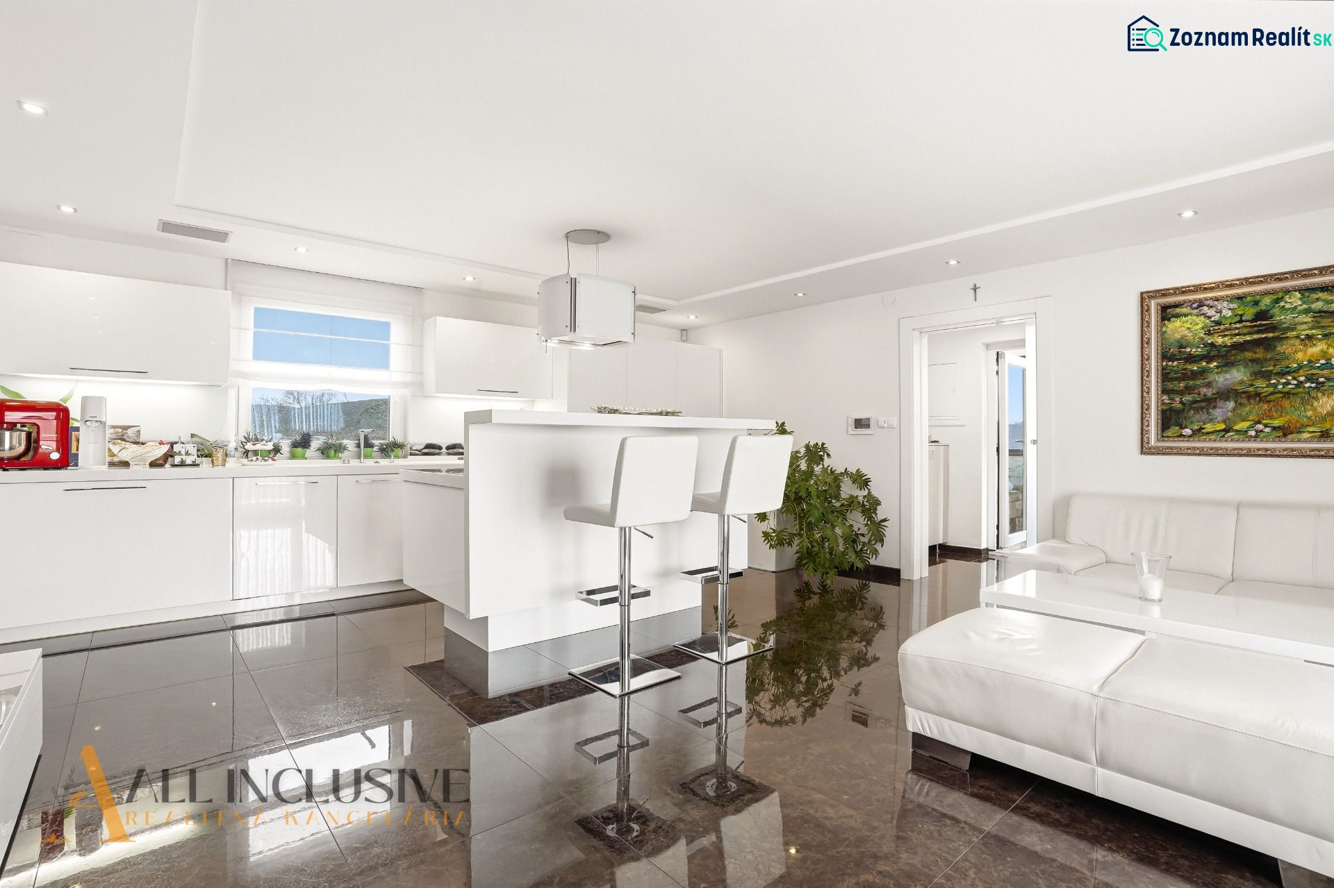 A bright kitchen in a family house with white furniture and glossy tiles.