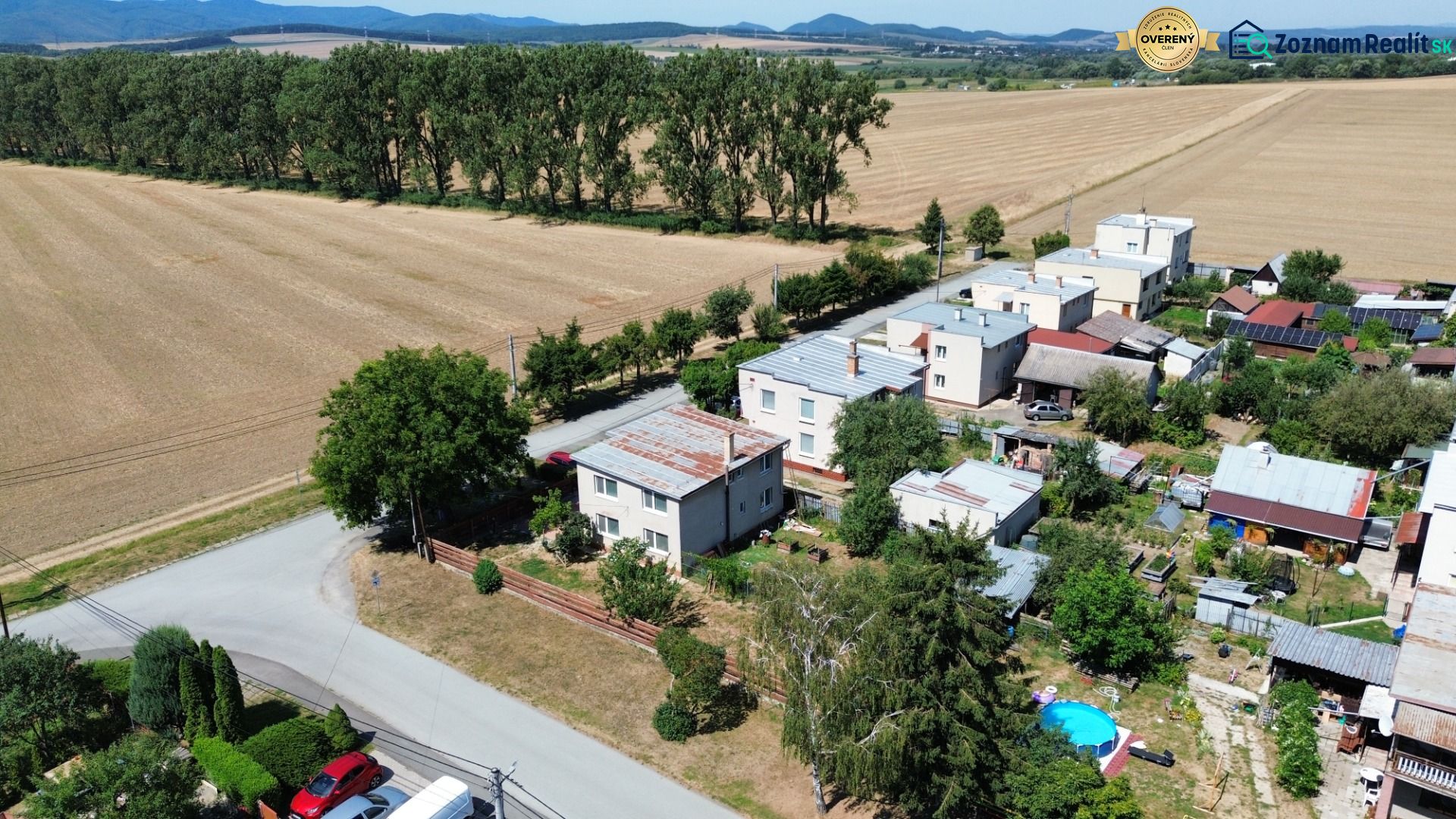 Family houses in Kráľovce on a street surrounded by fields and trees by the road.