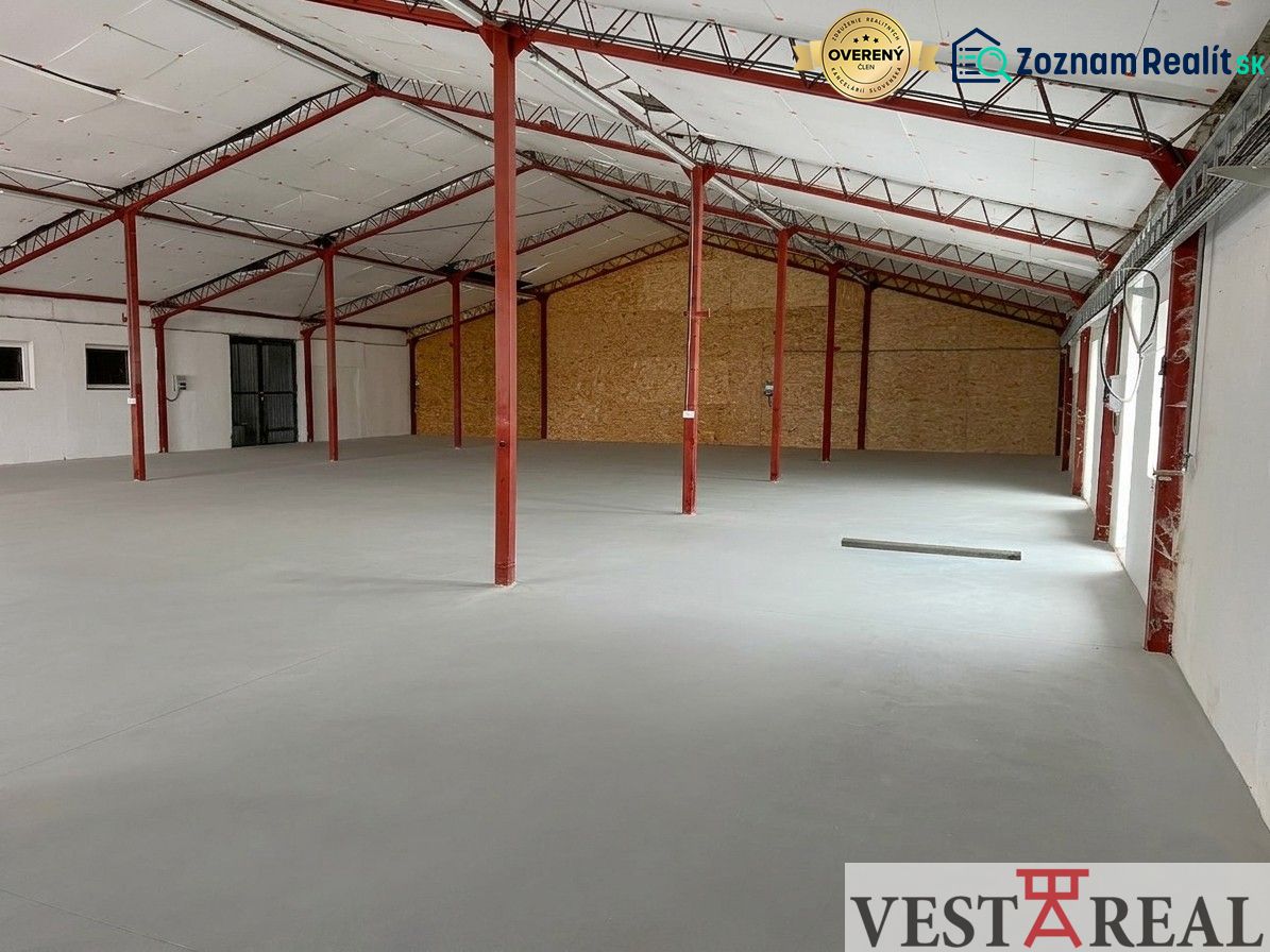 A spacious interior of a hall with iron beams and a white ceiling.