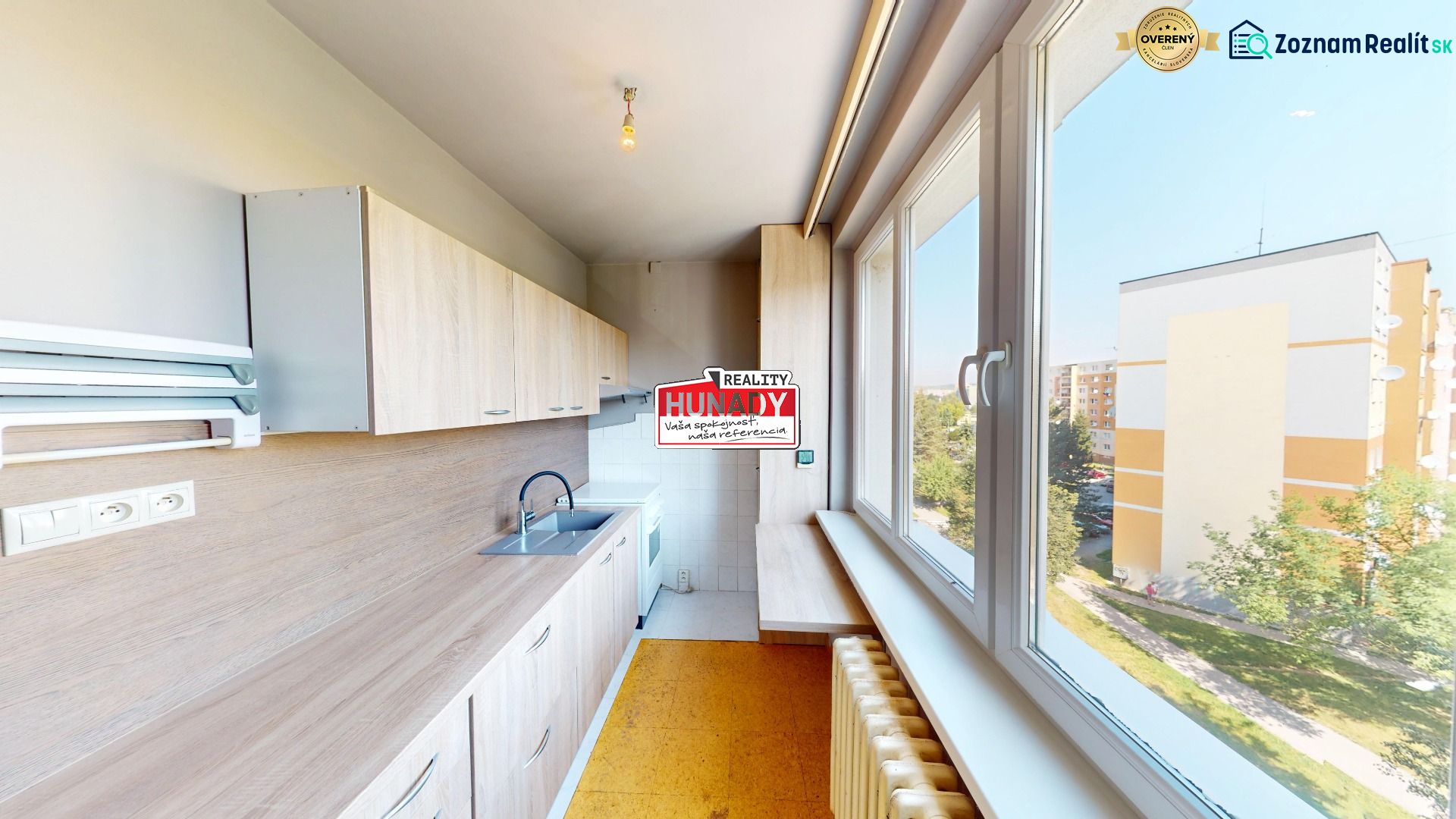 A kitchen with wooden decor and a large window in a 3-room apartment.