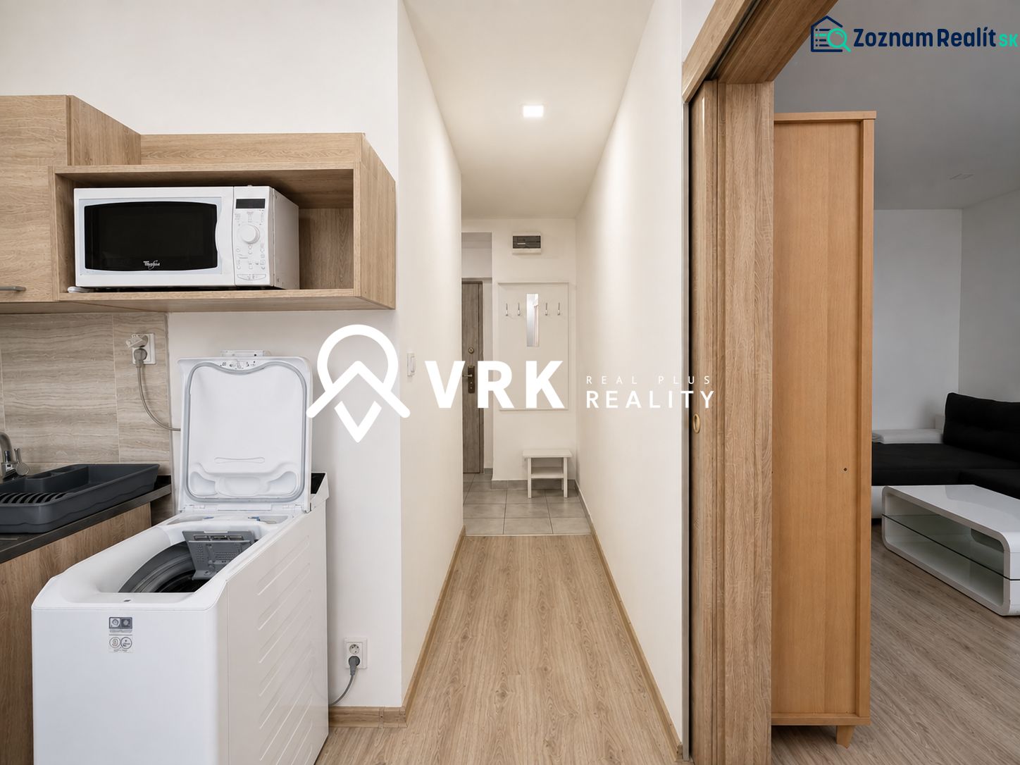 Cozy interior of a studio apartment with a kitchenette and a microwave, wooden decor flooring.