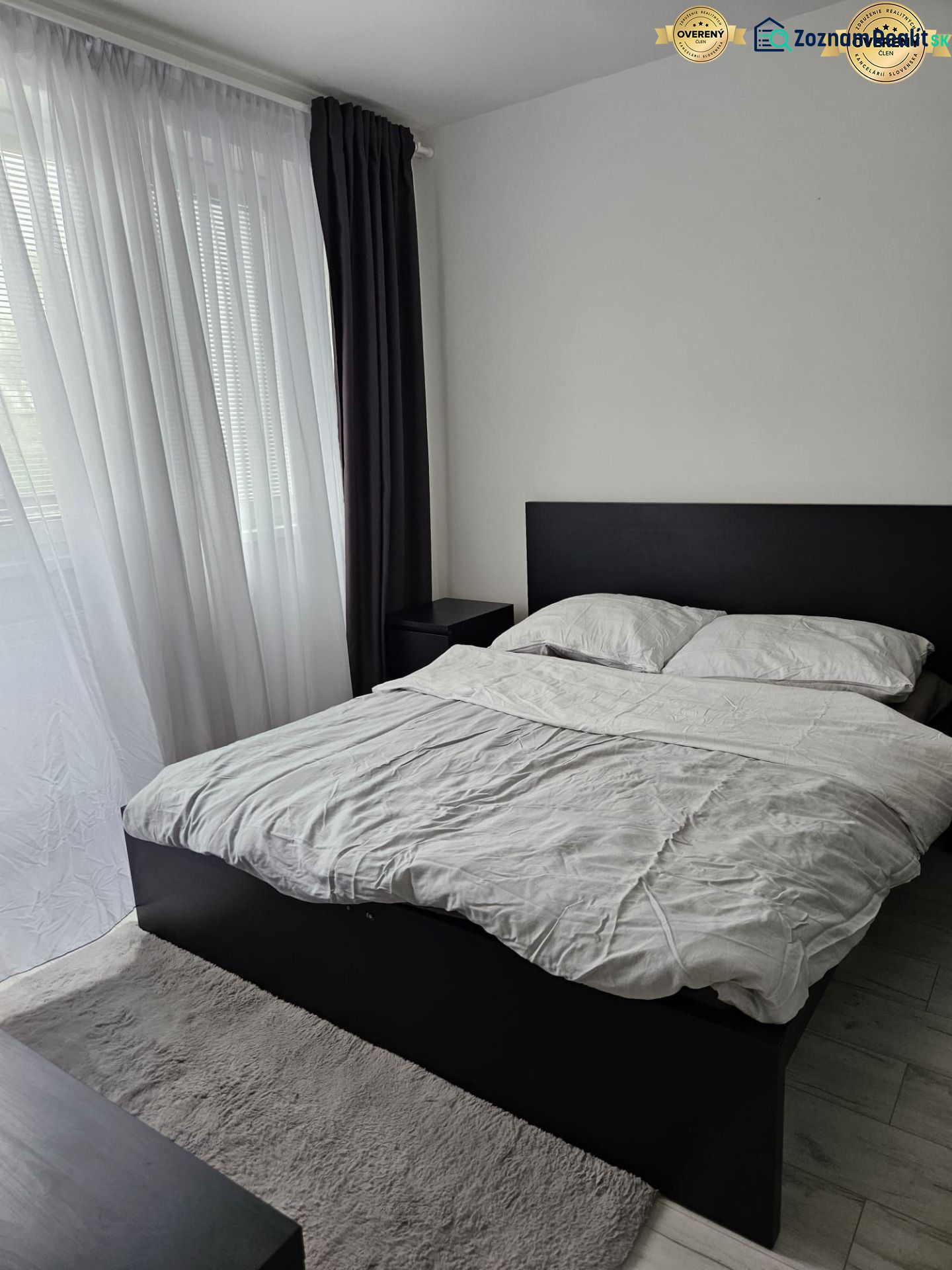 A bedroom with a bed and curtains in a 4-room apartment with a wooden decor floor.