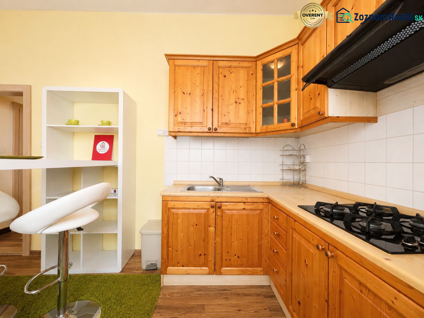 A kitchen in a studio apartment with wooden cabinets and a wooden-patterned floor.