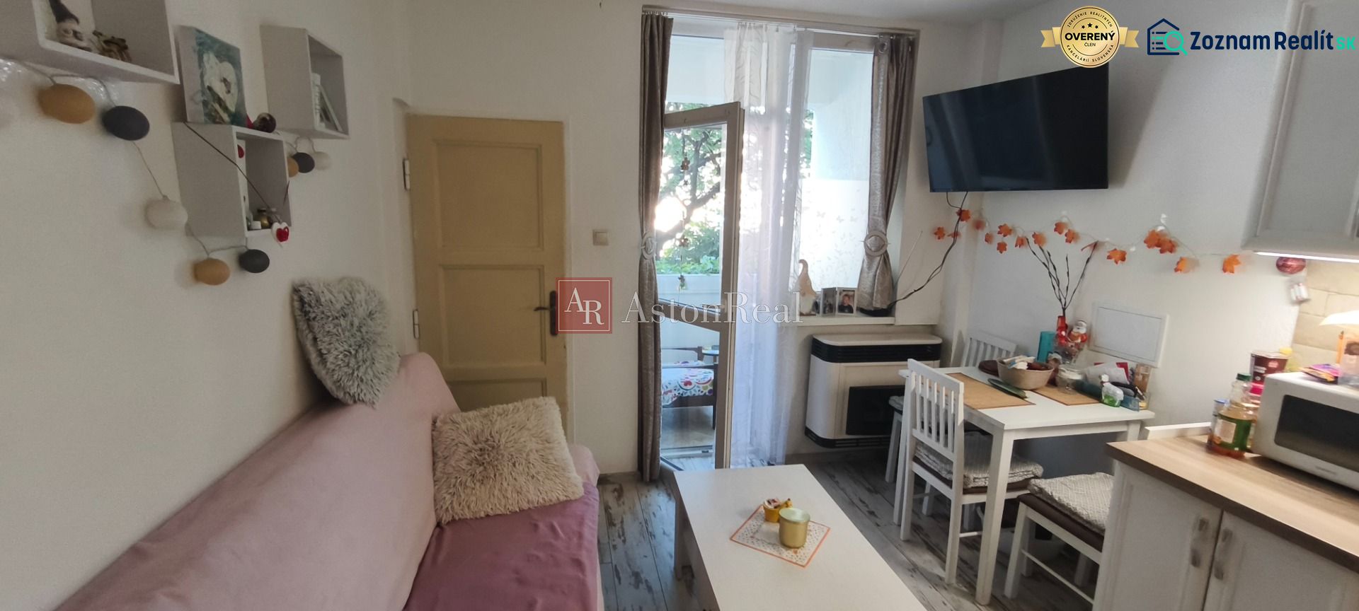 Living room in a one-room apartment with a sofa, dining table, and balcony.