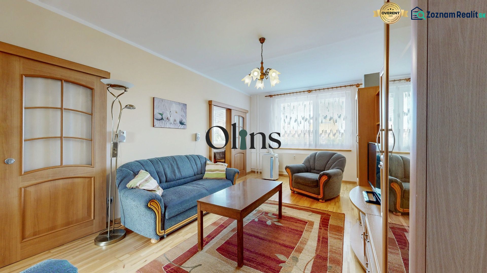 Living room in a three-room apartment with a wooden decor floor and blue seating.