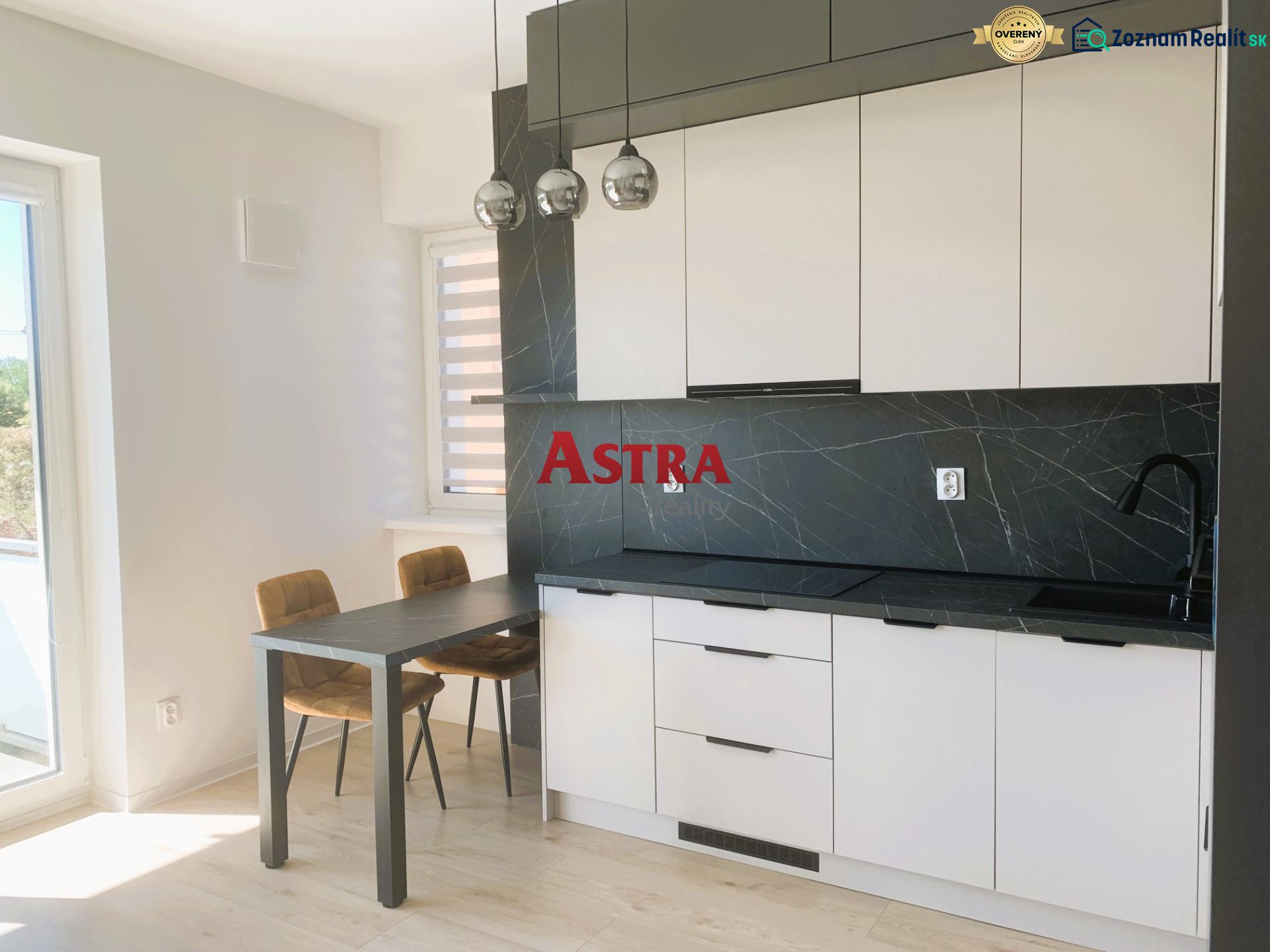 A kitchen in a 3-room apartment with a black countertop and table, and a floor with a wooden decor.