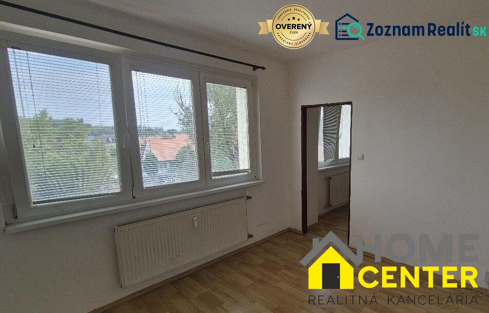 A room with white walls, large windows, and a floor with a wooden design.