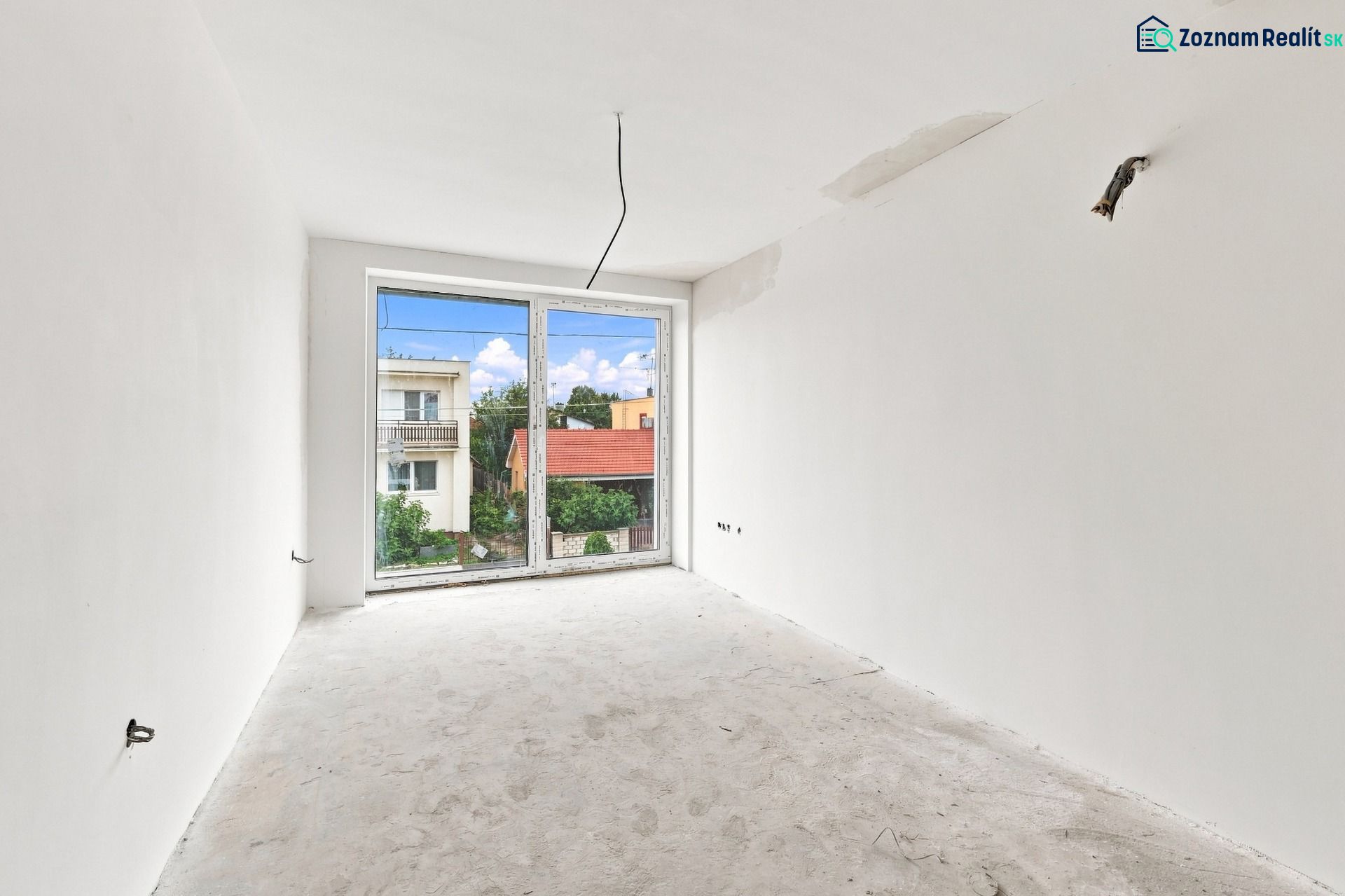 An empty room with a view from the window in a family house, without flooring.