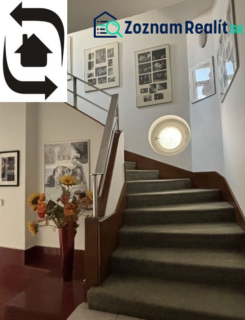 The staircase of the villa with a carpet, flower decorations, and artistic frames on the walls.