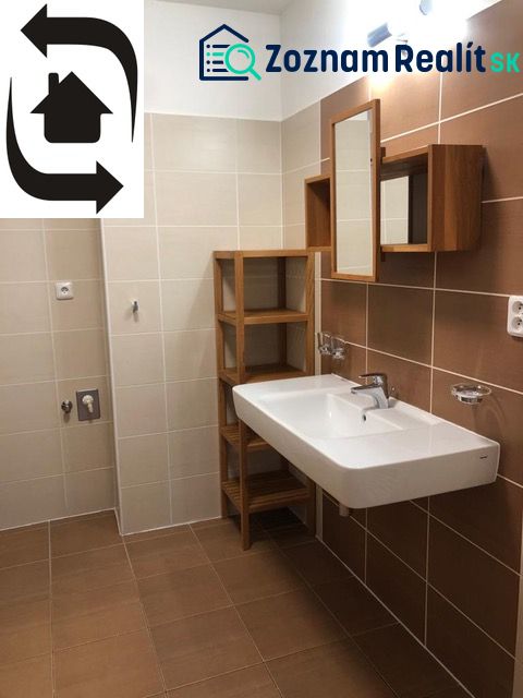 Bathroom in a 2-room apartment with brown tiles and a white sink.