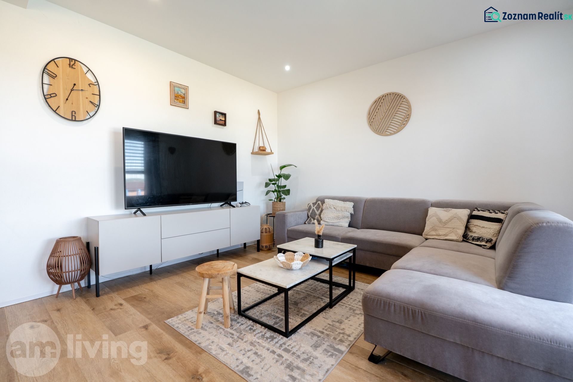 Living room in a family house with a wooden decor floor and a large gray sofa.