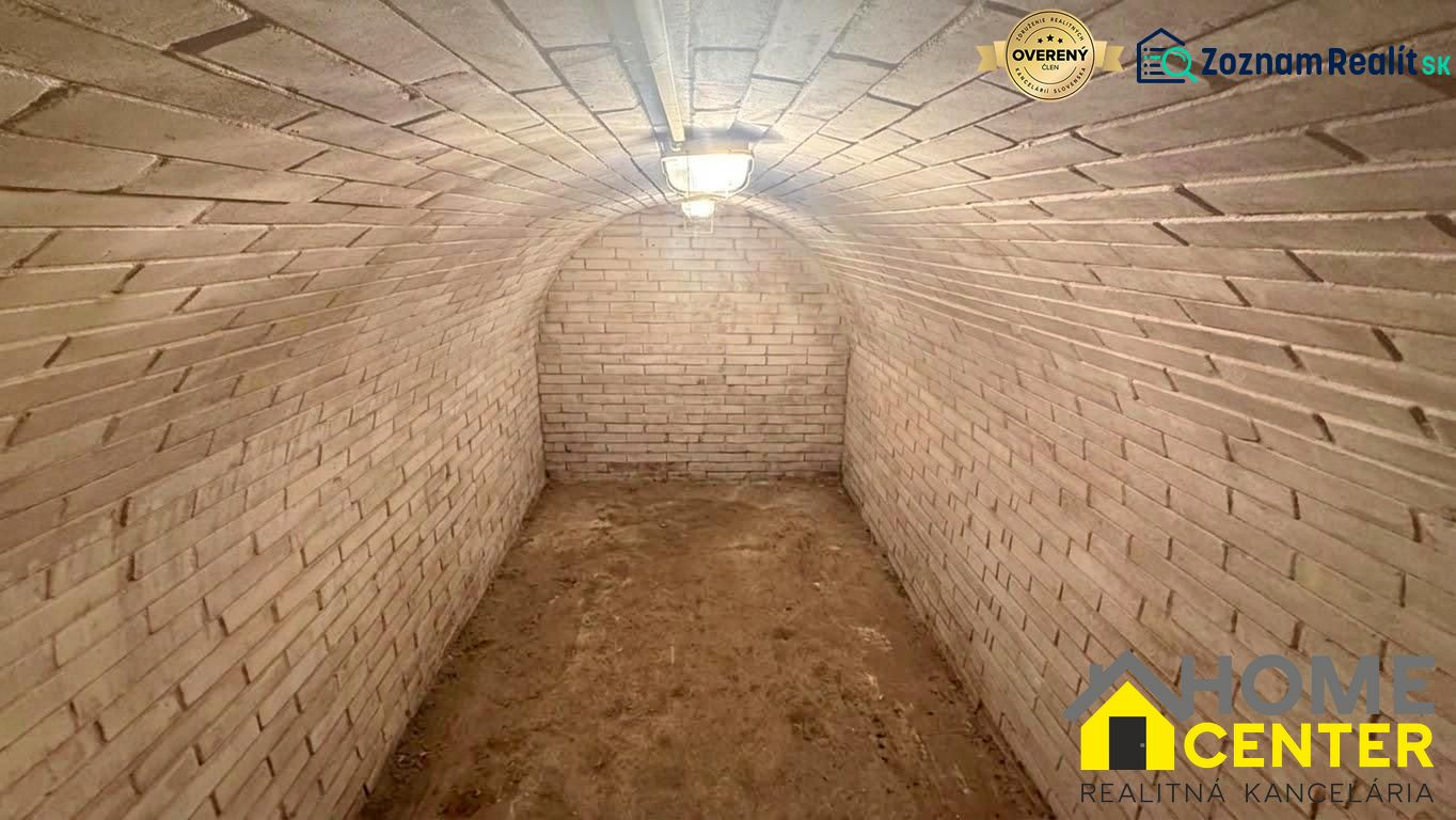 A brick-walled cellar in a cottage with an undecorated floor.