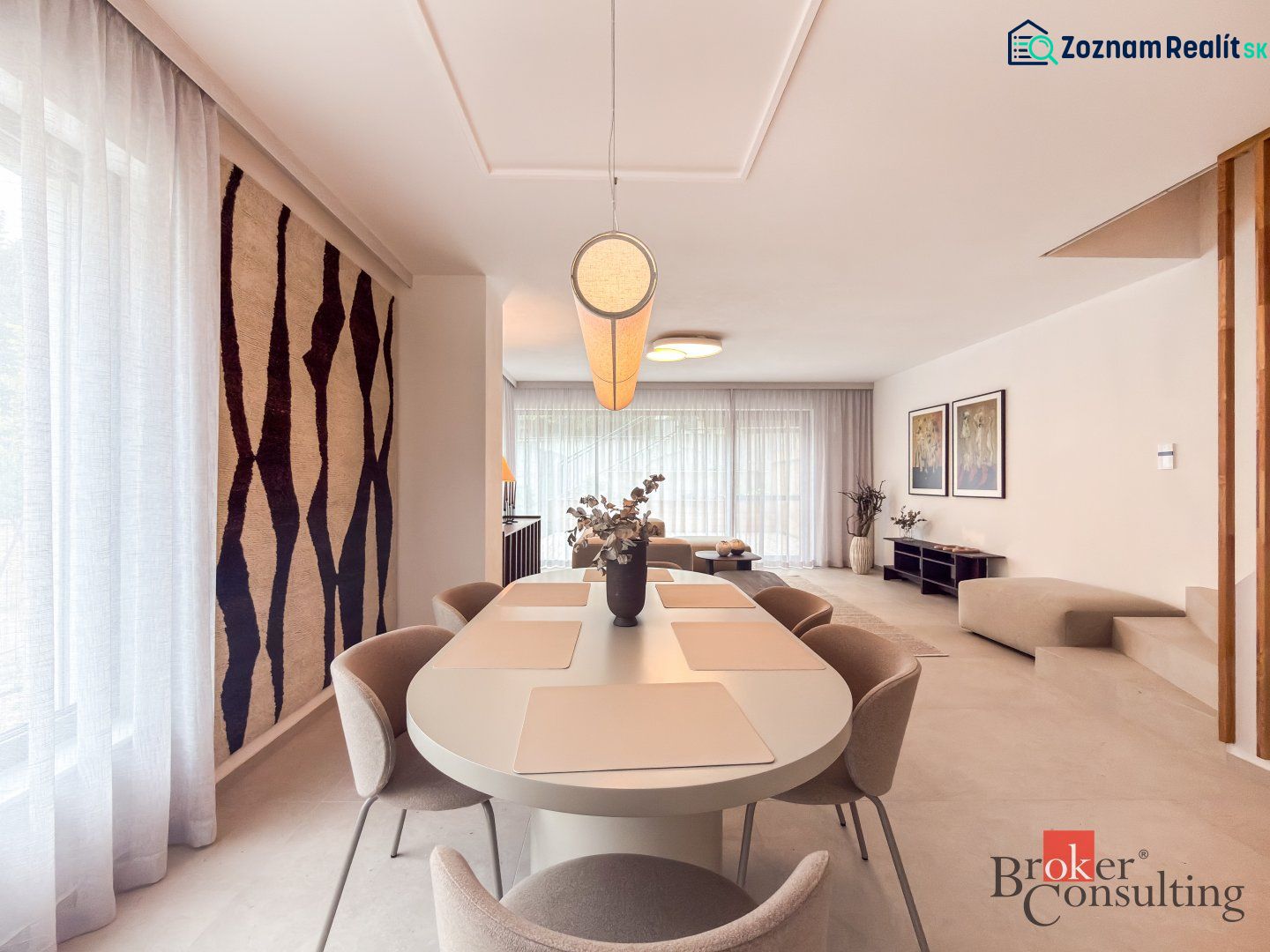 Dining room in a 4-room apartment with large windows and a decorative carpet on the wall.
