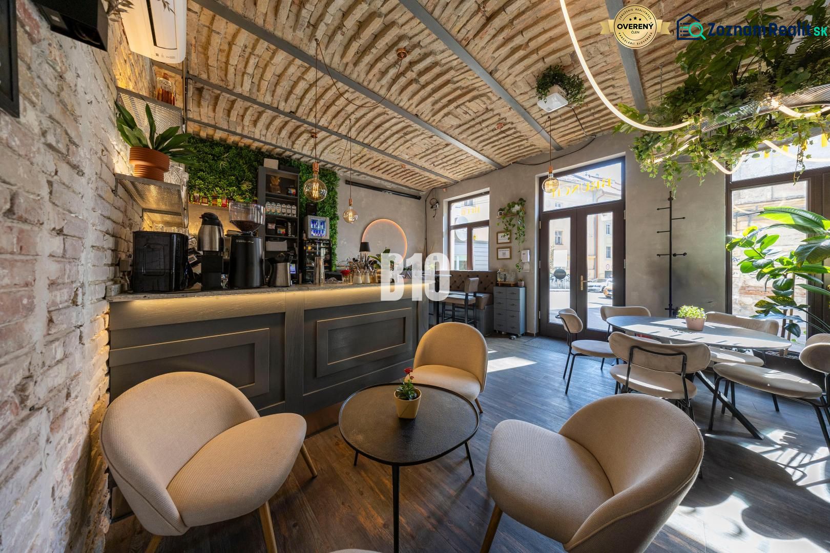 An interior with a bar surrounded by plants, a floor with a wooden decor, comfortable seating.