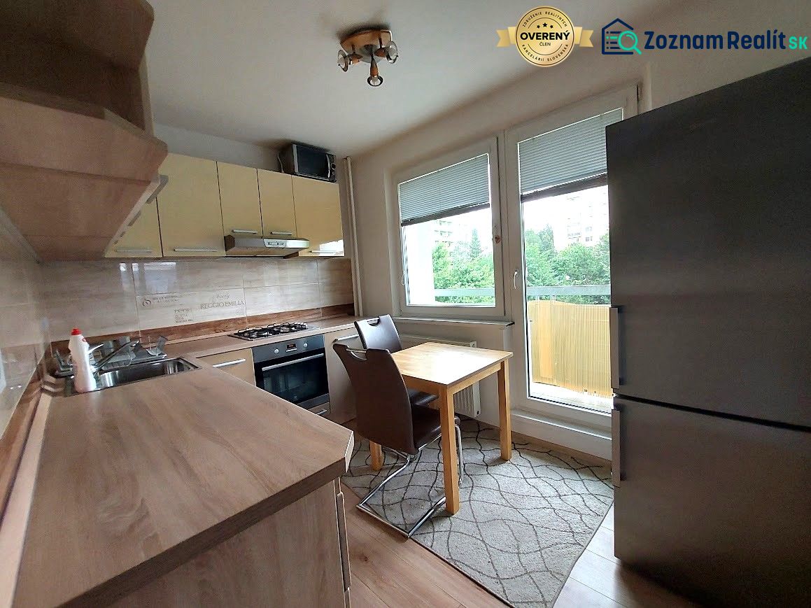 A kitchen in a 3-room apartment with a wooden decor floor, light cabinets, and appliances.