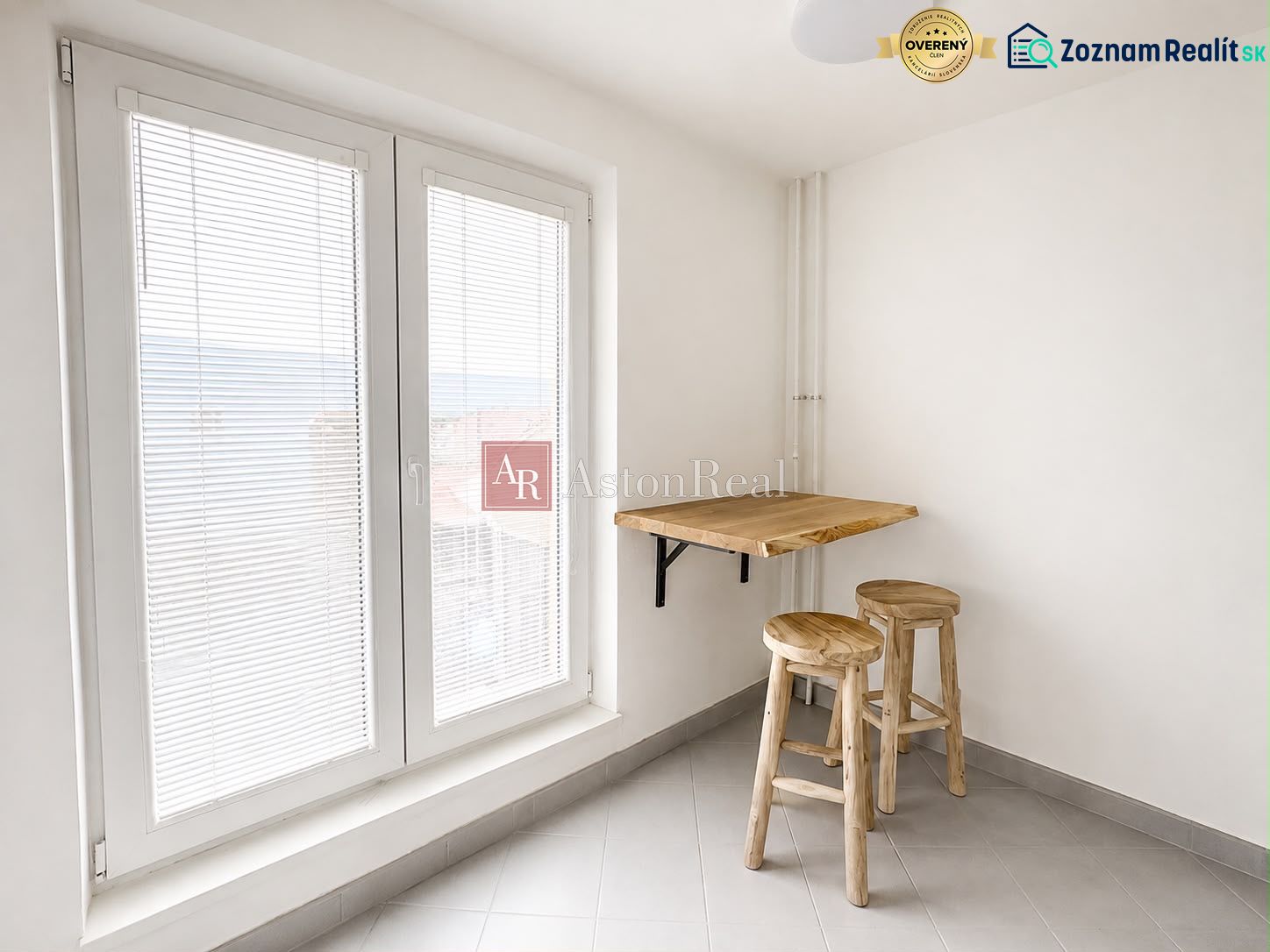 Simple kitchen area with wooden decor and a large window in a two-room apartment.