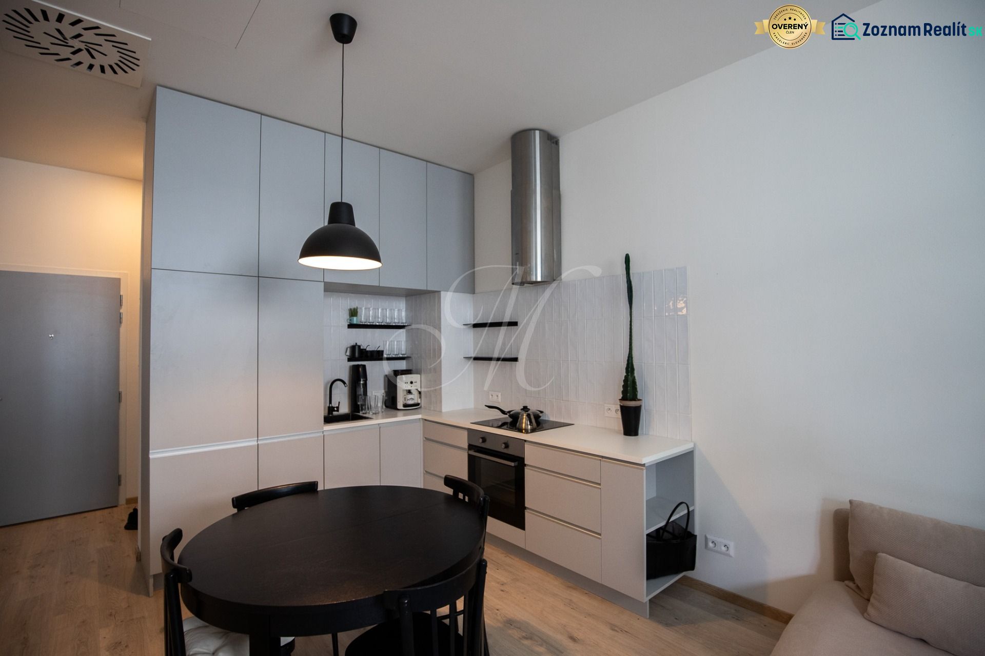 A kitchen in a 2-room apartment with a black table and a wooden decor floor.
