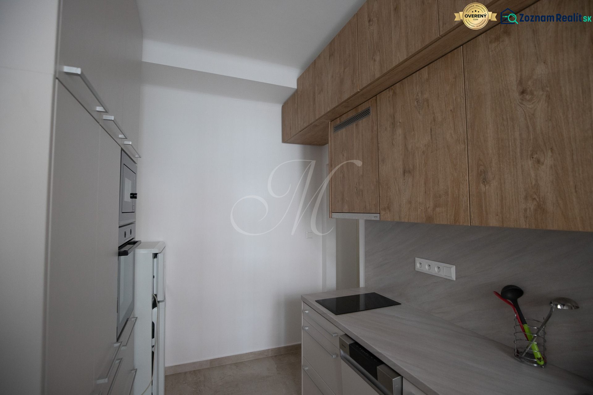 A kitchen in a studio apartment with wooden cabinets and modern appliances.