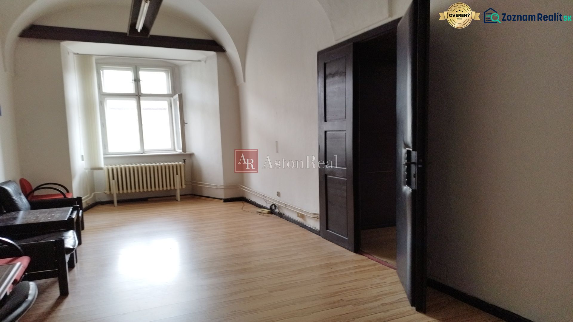 Interior of commercial premises with wood-effect flooring, older radiators, arched ceiling.