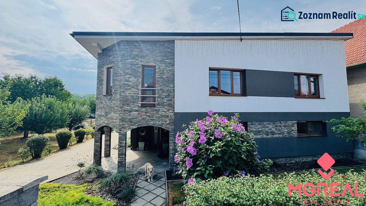 A family house in Radobica with a stone facade, a garden, and flowers in front of the building.