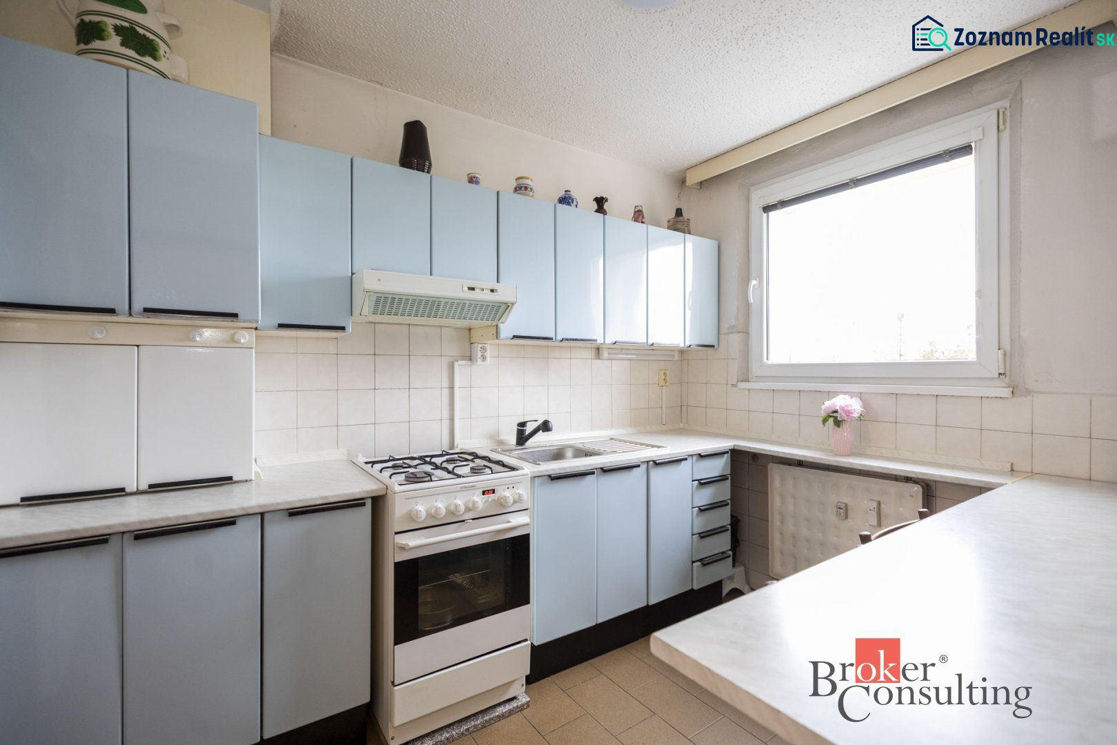 A kitchen in a 4-room apartment with light blue cabinets and a white tiled wall.
