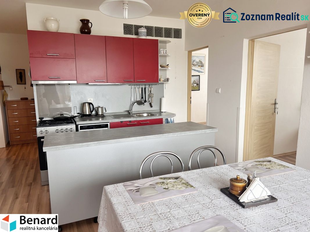 A kitchen with a table, cabinets, and a floor with a wood decor in a 3-room apartment.