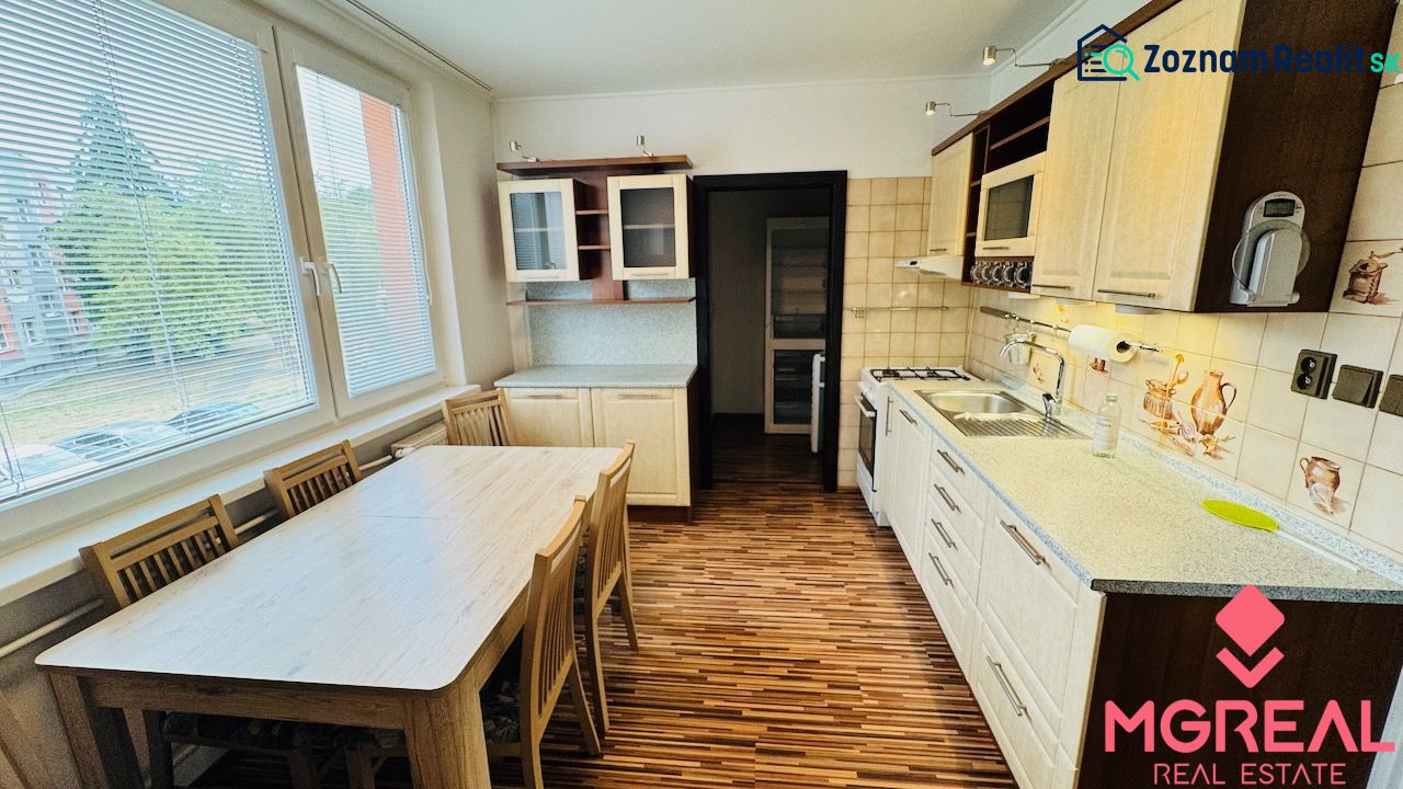 A kitchen with a wooden decor floor in a 3-room apartment, a dining table by the window.